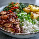 A close-up of Teriyaki Chicken and Rice Bowl garnished with scallions and sesame seeds, highlighting the glossy sauce and vibrant veggies.