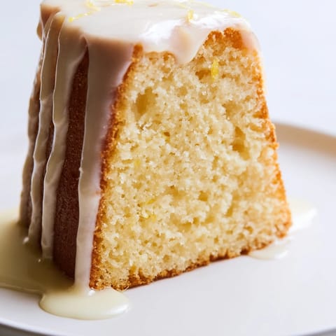 Freshly baked Lemon Pound Cake with a golden crust, dusted with powdered sugar and sliced on a wooden board.