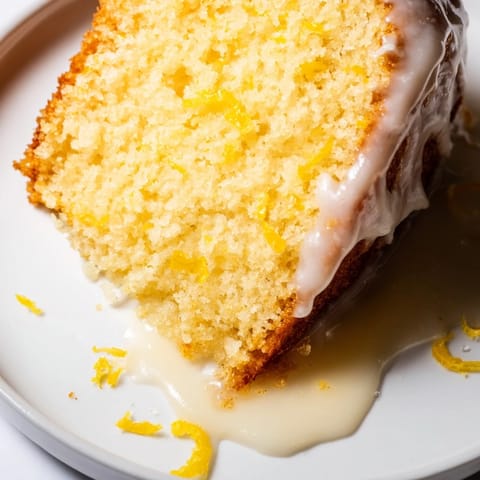Close-up of Lemon Pound Cake drizzled with tangy lemon glaze, topped with fresh blueberries and mint garnish.
