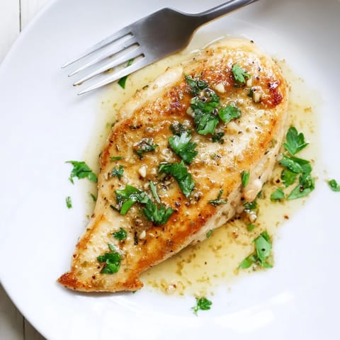 A close-up of succulent Lemon Pepper Chicken with vibrant lemon zest and cracked black pepper, sizzling in a buttery skillet.