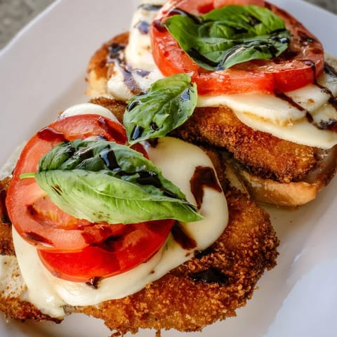 Crispy Chicken Caprese Sandwich on a rustic board, featuring golden chicken, ripe tomato slices, creamy mozzarella, and fresh basil on ciabatta.