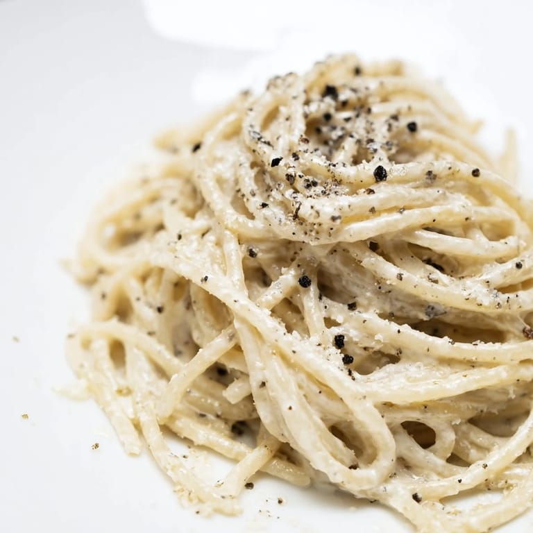 A rustic skillet of Spaghetti Cacio e Pepe steams beside a glass of crisp Pinot Grigio, perfect for a quick weeknight dinner.