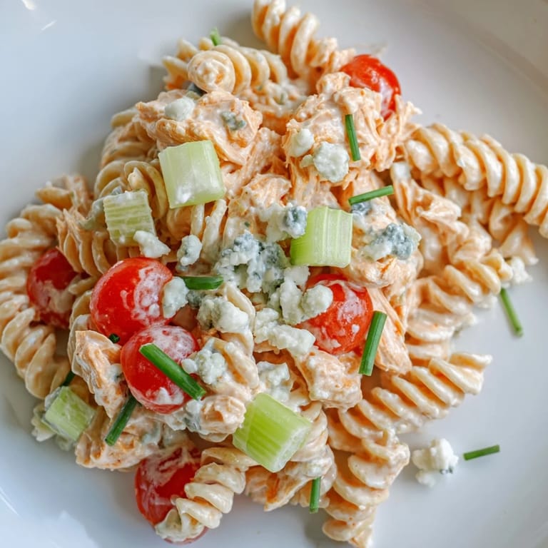 Chilled rotini pasta salad featuring spicy buffalo chicken, fresh vegetables, and blue cheese crumbles, perfect for a summer picnic.