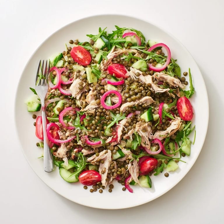 A close-up of the Lentil & Chicken Spring Salad with pickled onions and cherry tomatoes on a white plate, perfect for lunch.  