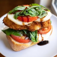 Golden, breaded chicken cutlets with melted mozzarella, layered with fresh tomato and basil on toasted ciabatta for a Crispy Chicken Caprese Sandwich.