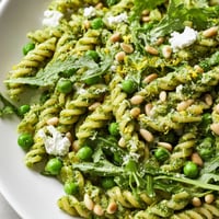 Close-up of Spring Green Pesto Pasta Salad with vibrant basil sauce, sweet peas, and peppery arugula.