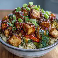 A close-up of a vibrant Quinoa Vegetable Teriyaki Bowl with golden crispy tofu and colorful stir-fried vegetables.