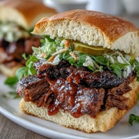 Mouthwatering BBQ brisket sliders with tangy sauce and crunchy slaw, served warm on soft buns for a festive bite.  